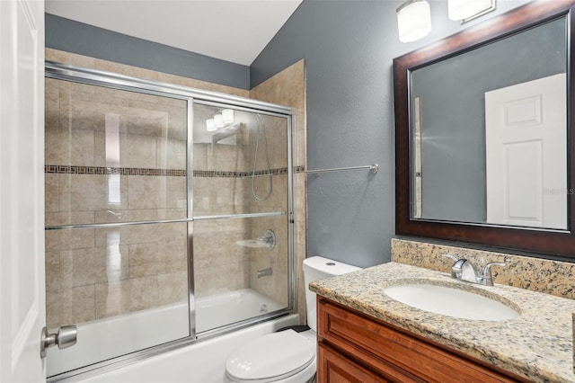 full bath with vanity, a textured wall, lofted ceiling, toilet, and shower / bath combination with glass door