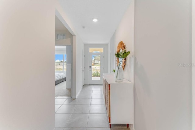 hall featuring baseboards, visible vents, and light tile patterned floors