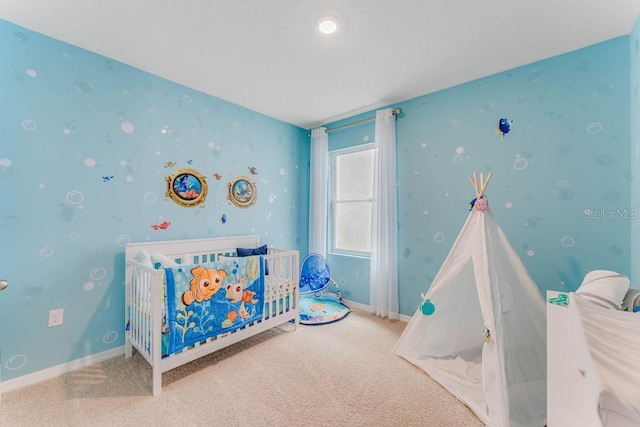 carpeted bedroom with a crib, baseboards, and wallpapered walls