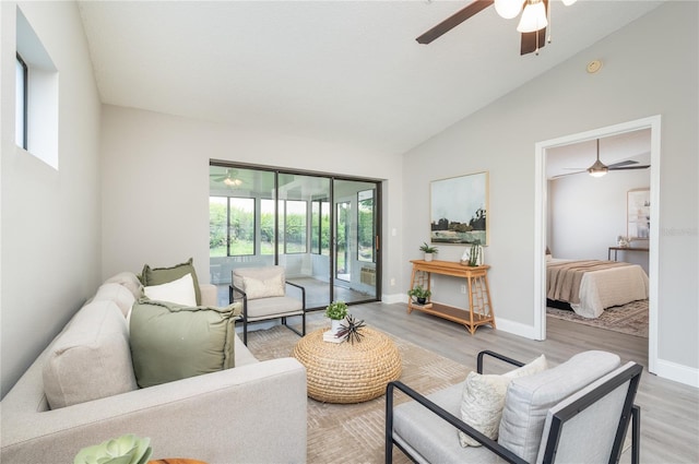 living area featuring baseboards, ceiling fan, light wood-style flooring, and lofted ceiling