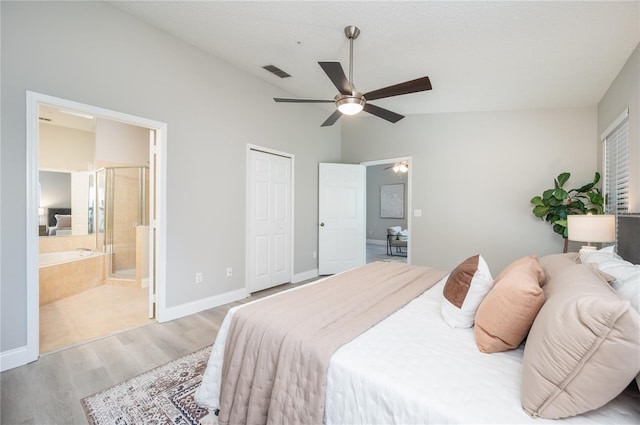 bedroom with light wood-style flooring, baseboards, ensuite bathroom, lofted ceiling, and visible vents