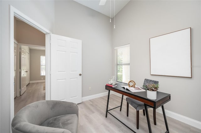 office area with high vaulted ceiling, baseboards, and light wood-type flooring