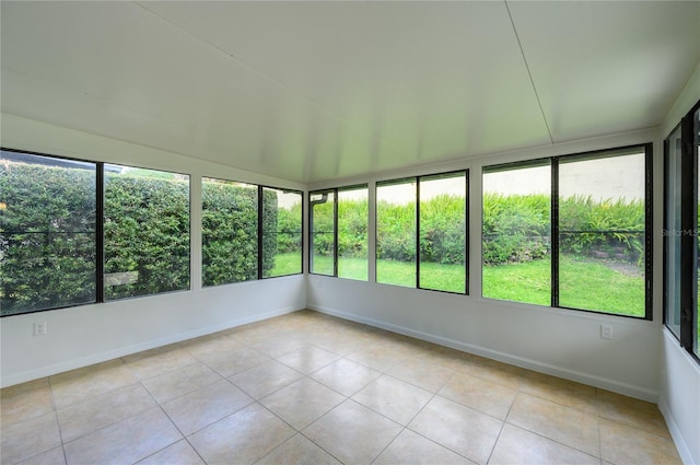unfurnished sunroom featuring tile patterned floors, plenty of natural light, and baseboards
