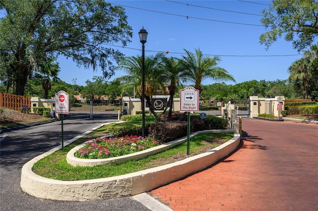 view of road featuring traffic signs, a gated entry, curbs, and a gate