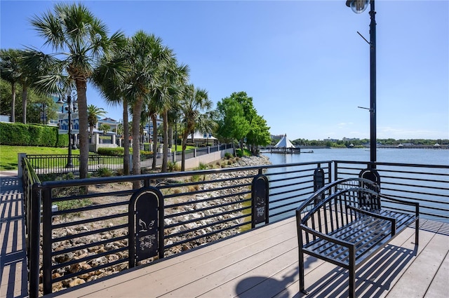 wooden terrace featuring a water view and fence