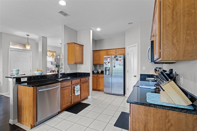 3917 Pemberly Pines Cir, Saint Cloud, FL 34769 - kitchen with brown cabinetry, visible vents, a sink, dark stone counters, and stainless steel appliances