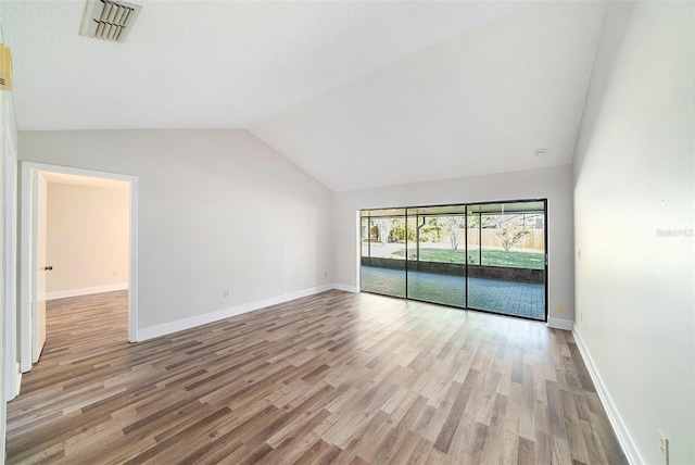 interior space featuring light wood-style floors, baseboards, vaulted ceiling, and visible vents