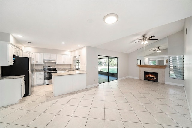 kitchen with appliances with stainless steel finishes, a sink, light tile patterned floors, open floor plan, and under cabinet range hood
