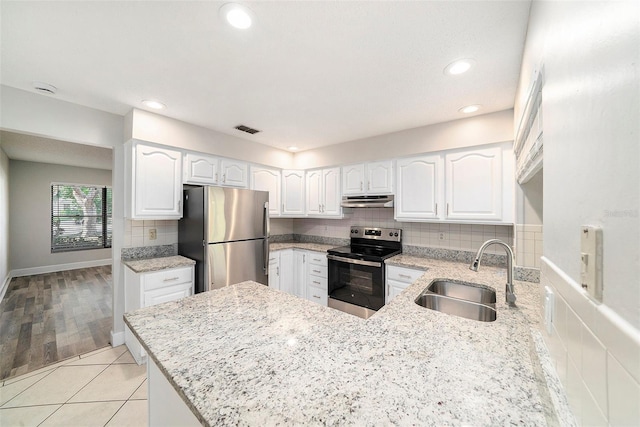 kitchen with visible vents, under cabinet range hood, light stone counters, a sink, and stainless steel appliances