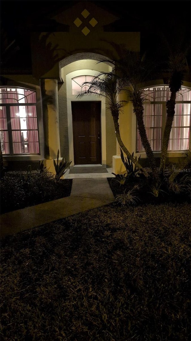 exterior entry at twilight featuring stucco siding