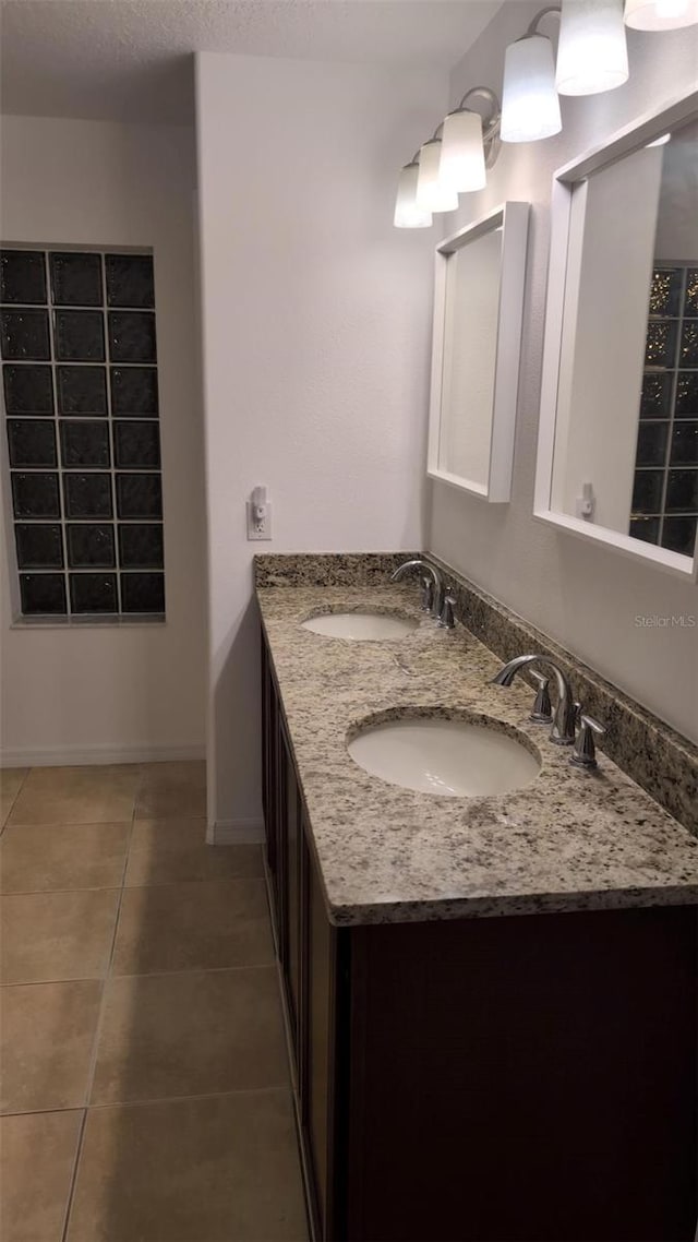bathroom with double vanity, baseboards, a sink, and tile patterned flooring