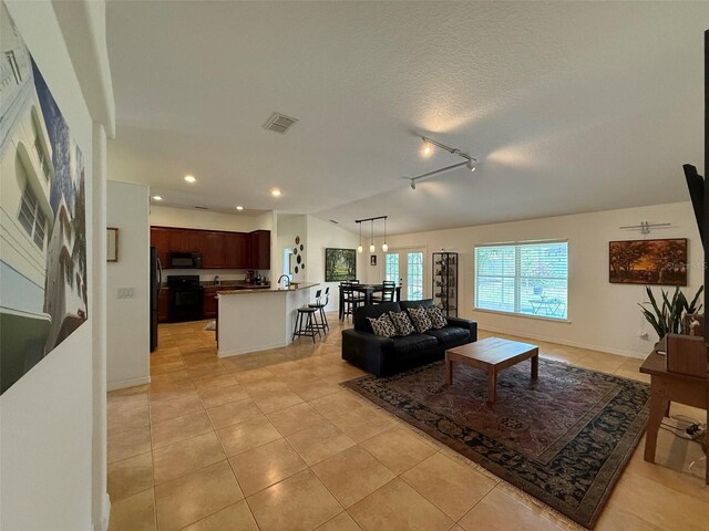 4920 E Lake Cove Blvd, Saint Cloud, FL 34771 - living room featuring light tile patterned flooring, track lighting, recessed lighting, baseboards, and a textured ceiling