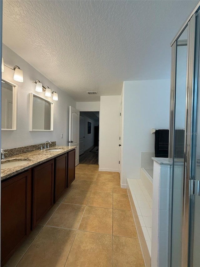 4920 E Lake Cove Blvd, Saint Cloud, FL 34771 - bathroom featuring double vanity, a bath, tile patterned floors, a textured ceiling, and baseboards