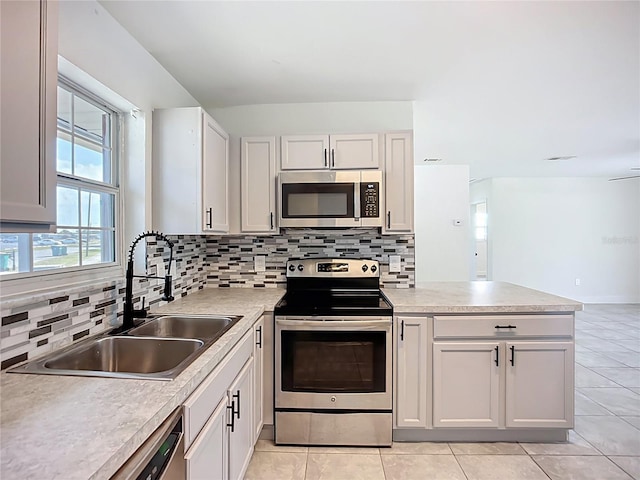 22131 Bahama Ave, Port Charlotte, FL 33952 - kitchen featuring a sink, stainless steel appliances, a peninsula, light tile patterned floors, and backsplash