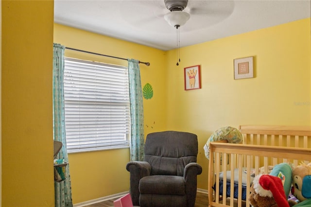 bedroom with a nursery area, multiple windows, baseboards, and ceiling fan