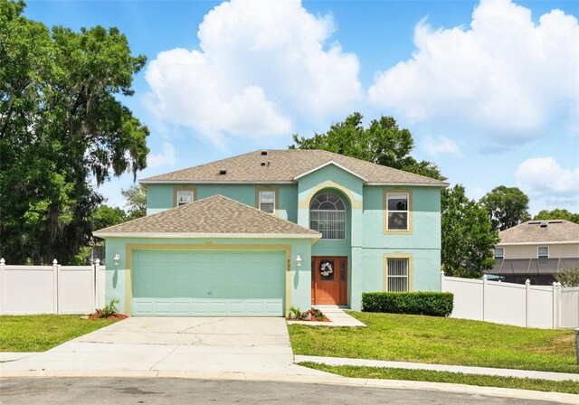 view of front of home featuring fence, a front lawn, a garage, stucco siding, and concrete driveway