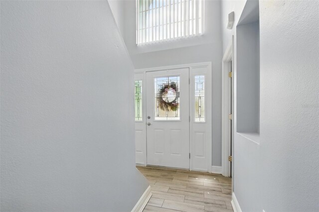 interior space with baseboards, a high ceiling, and light wood-style flooring