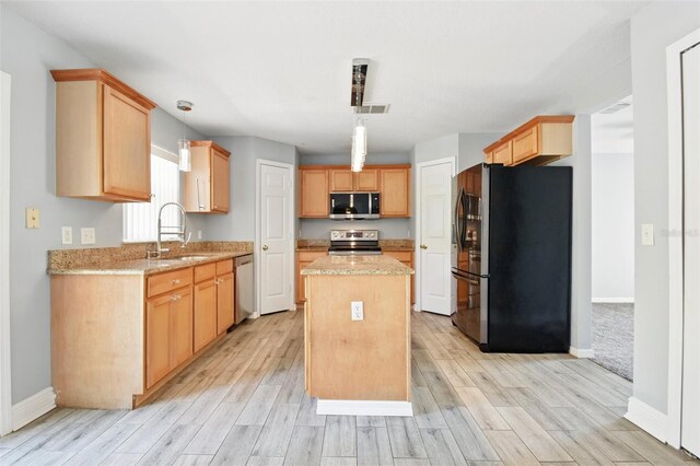 kitchen featuring a center island, a sink, light wood-type flooring, and stainless steel appliances
