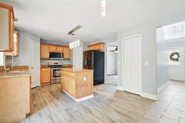 kitchen with stainless steel appliances, light wood-style floors, a sink, and a center island
