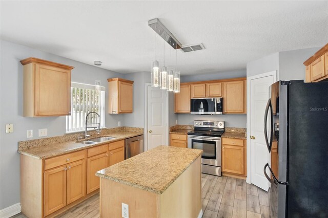 kitchen featuring visible vents, light brown cabinetry, a sink, stainless steel appliances, and light wood-style flooring