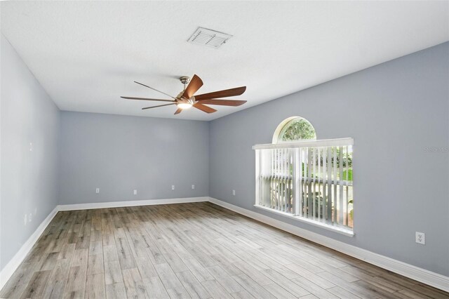 spare room with a ceiling fan, baseboards, visible vents, and wood finished floors