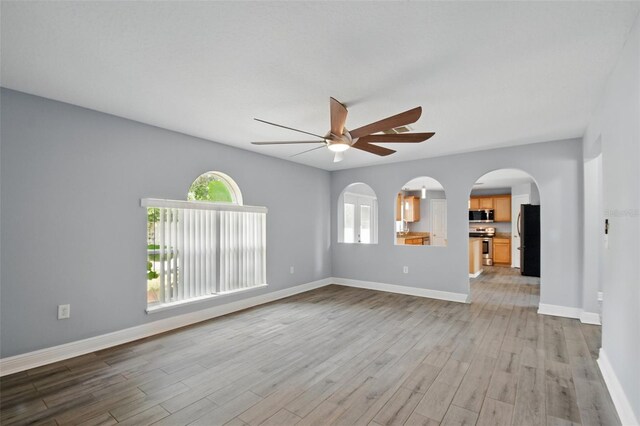 unfurnished room with a ceiling fan, plenty of natural light, and light wood finished floors