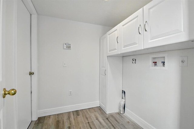 clothes washing area featuring cabinet space, electric dryer hookup, light wood-style flooring, and washer hookup