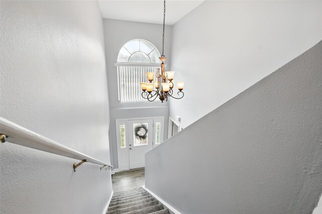 staircase with baseboards, a chandelier, and a high ceiling