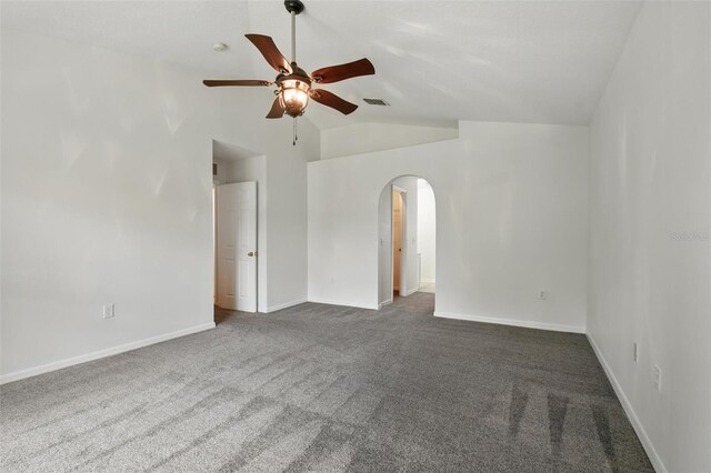 unfurnished room featuring lofted ceiling, dark colored carpet, baseboards, ceiling fan, and arched walkways