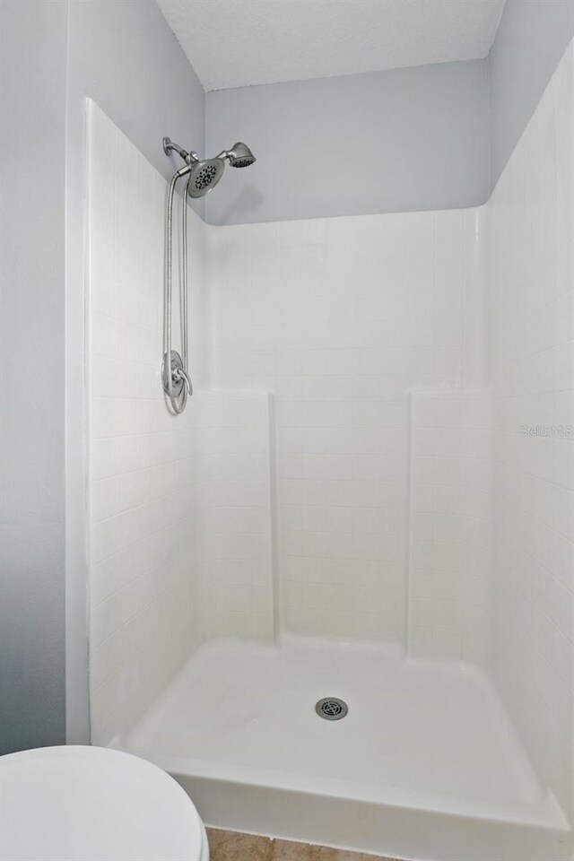full bath featuring toilet and a tile shower