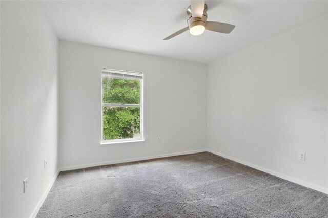 carpeted spare room featuring baseboards and ceiling fan