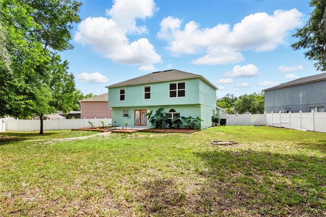 back of property featuring a fenced backyard, french doors, stucco siding, and a yard