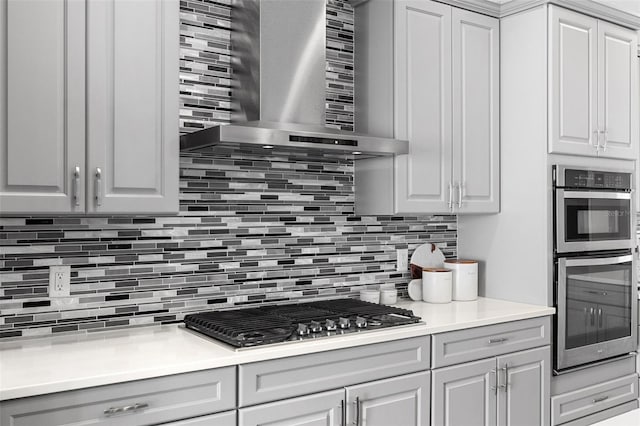 8848 Bismarck Palm Dr, Winter Garden, FL 34787 - kitchen featuring stainless steel appliances, gray cabinets, wall chimney exhaust hood, and tasteful backsplash
