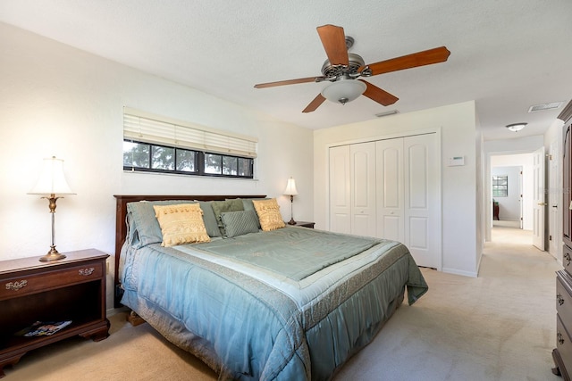 bedroom with light colored carpet, a closet, visible vents, and ceiling fan
