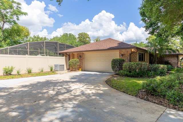 ranch-style home featuring an attached garage, central AC, fence, concrete driveway, and brick siding