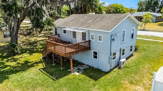 rear view of property with a lawn, ac unit, roof with shingles, and a wooden deck