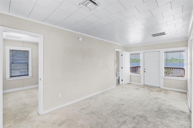 carpeted empty room with crown molding, baseboards, and visible vents