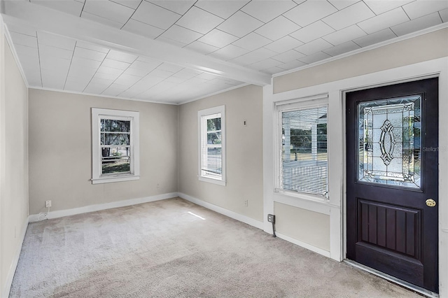 foyer entrance featuring crown molding, carpet flooring, baseboards, and a wealth of natural light