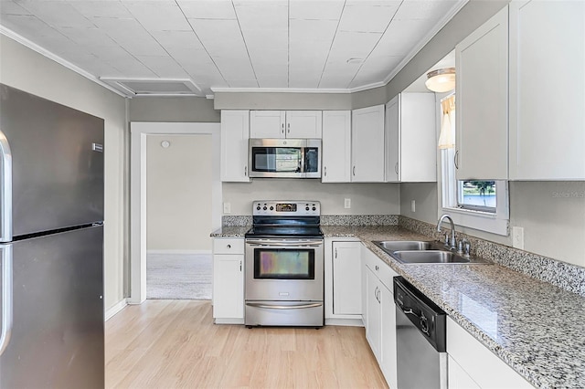 kitchen featuring crown molding, appliances with stainless steel finishes, a sink, white cabinets, and light wood-style flooring