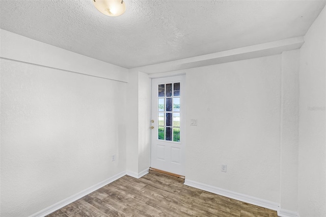 spare room featuring a textured ceiling, baseboards, and wood finished floors