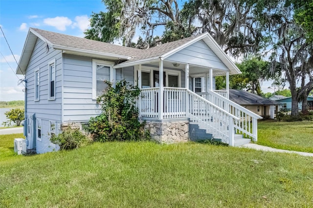 view of front of home featuring a porch, a shingled roof, and a front yard