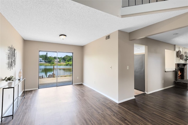 unfurnished living room with a textured ceiling, baseboards, wood finished floors, and visible vents