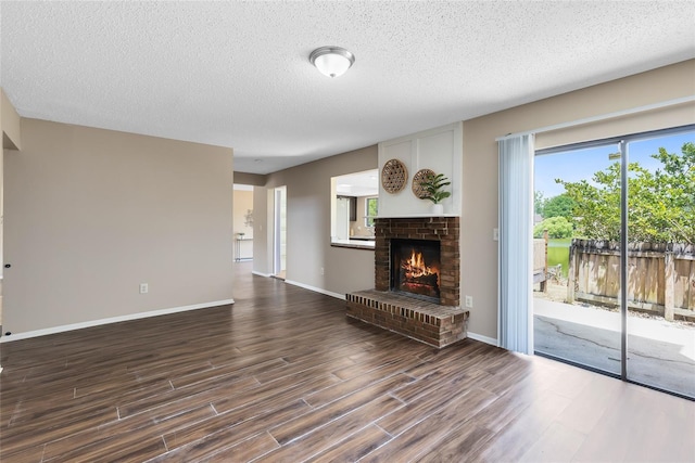 unfurnished living room featuring a textured ceiling, dark wood finished floors, baseboards, and a fireplace