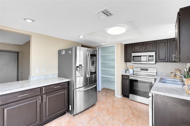 kitchen with visible vents, appliances with stainless steel finishes, a sink, light countertops, and a tray ceiling