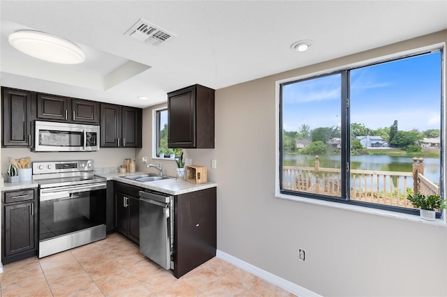 kitchen featuring visible vents, light countertops, a water view, a sink, and appliances with stainless steel finishes