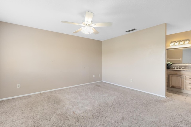 unfurnished bedroom featuring visible vents, a sink, baseboards, ensuite bathroom, and light carpet