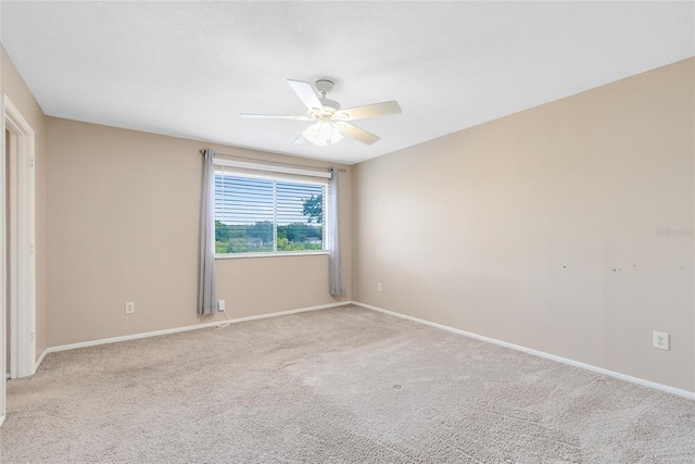 spare room with baseboards, ceiling fan, and light carpet