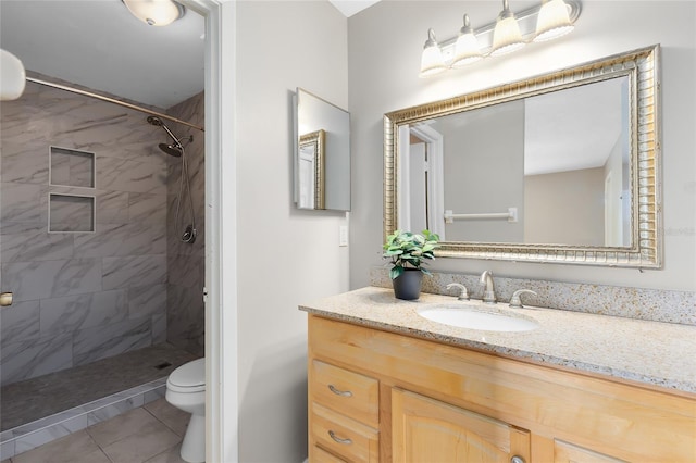 bathroom featuring vanity, tile patterned flooring, toilet, and tiled shower