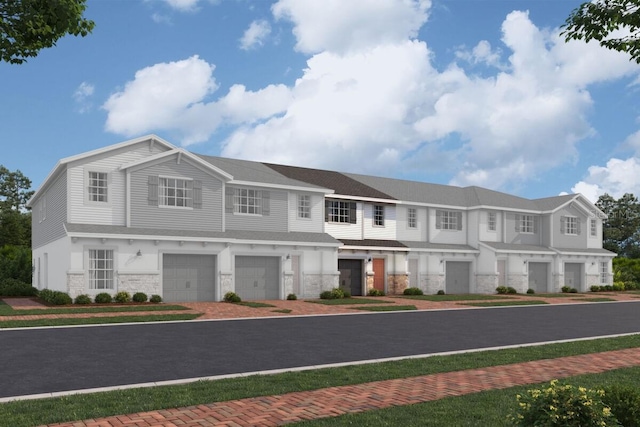 view of front of house featuring an attached garage, driveway, and stone siding