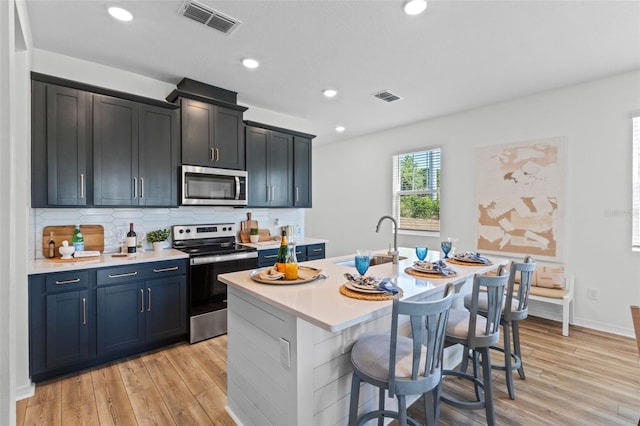 kitchen with visible vents, appliances with stainless steel finishes, a sink, light countertops, and light wood-style floors